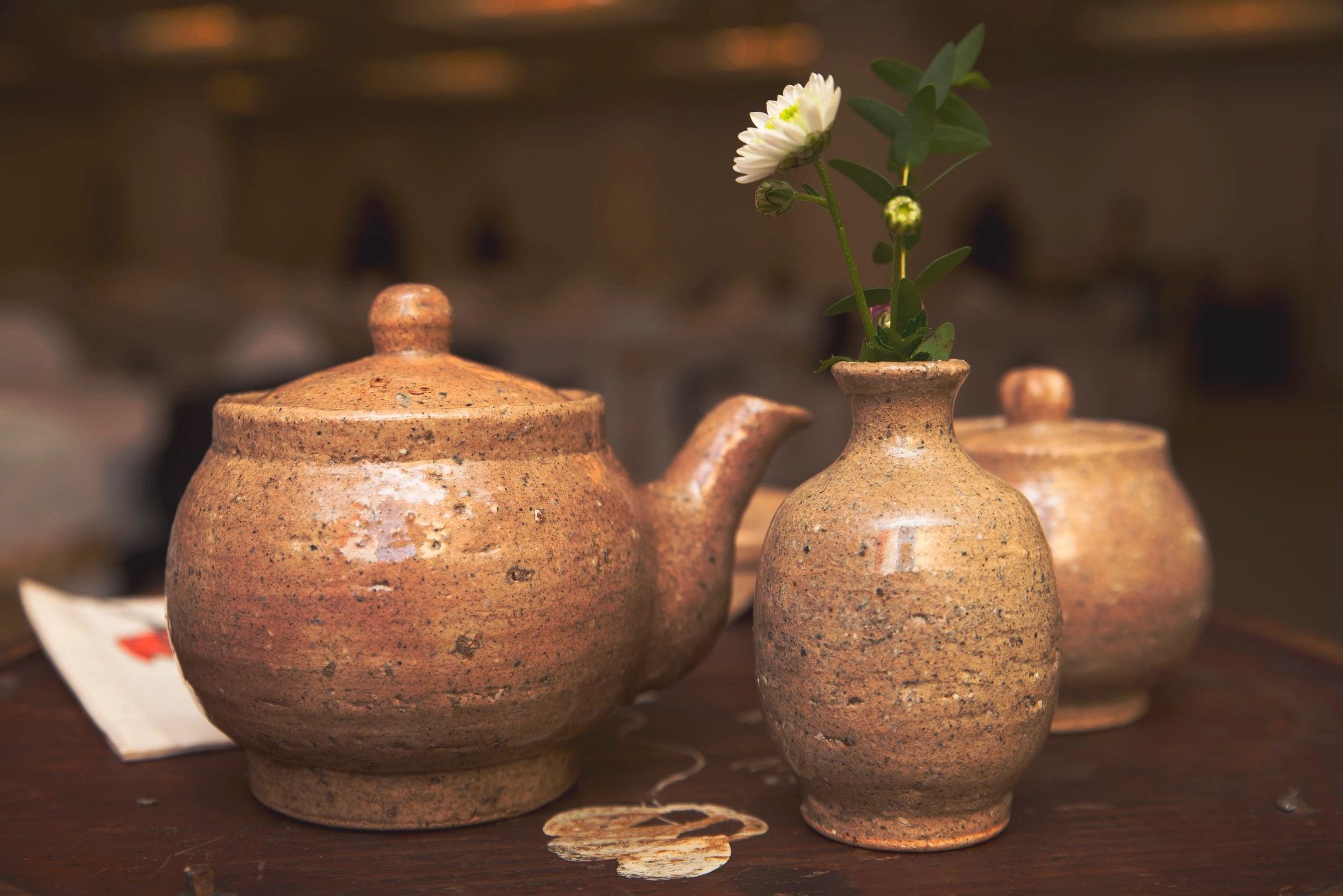 A tea pot and vase with a flower in it.