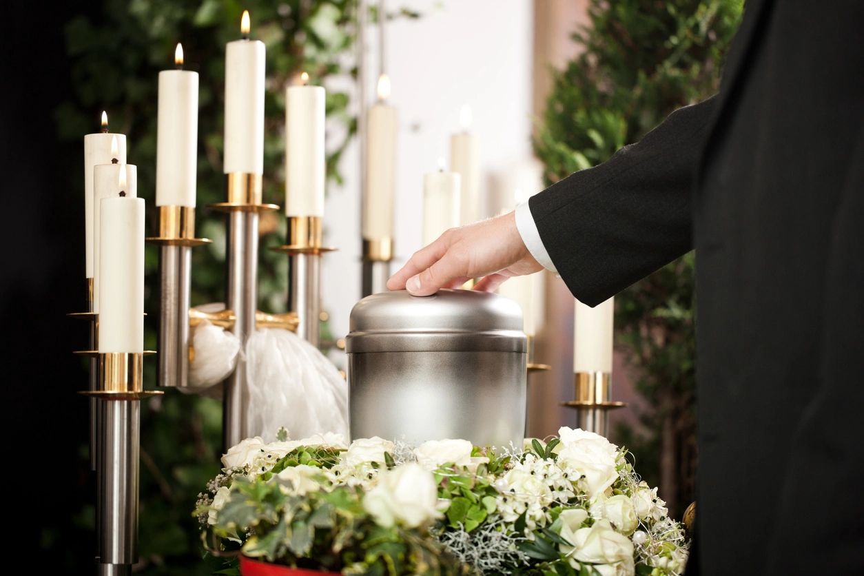 A person is holding a urn in front of candles.