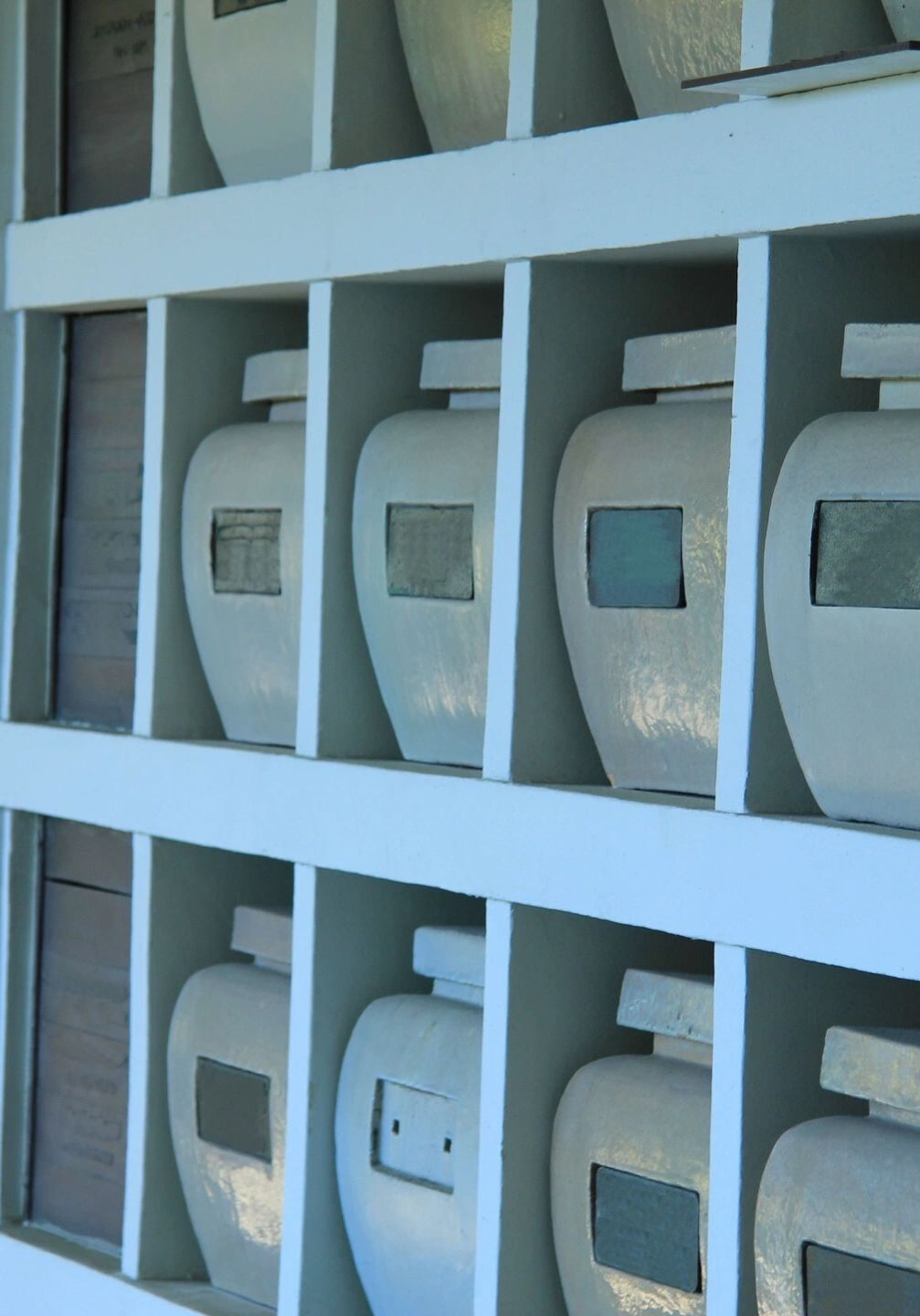 A wall of white shelves with many different types of masks.